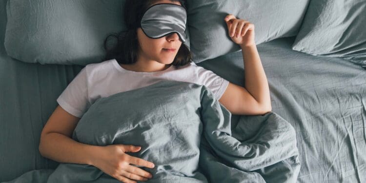 woman sleep in eye patch in grey bed. copy space