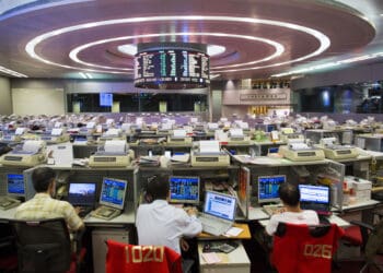 Stock traders sit at their desks facing an electronic board on the trading floor of the Hong Kong Stock Exchange in Hong Kong, China, on Tuesday, Aug. 13, 2013. Hong Kong Exchanges & Clearing Ltd., operator of the Hong Kong Stock Exchange, is scheduled to release second-quarter results tomorrow. Photographer: Jerome Favre/Bloomberg via Getty Images