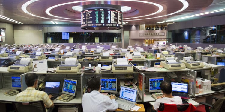 Stock traders sit at their desks facing an electronic board on the trading floor of the Hong Kong Stock Exchange in Hong Kong, China, on Tuesday, Aug. 13, 2013. Hong Kong Exchanges & Clearing Ltd., operator of the Hong Kong Stock Exchange, is scheduled to release second-quarter results tomorrow. Photographer: Jerome Favre/Bloomberg via Getty Images