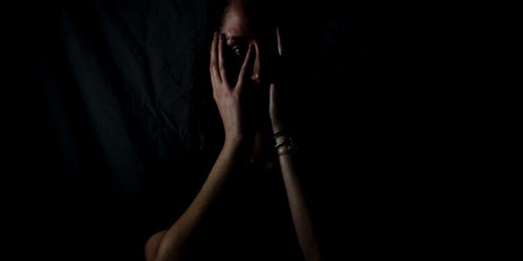 woman holding her face in dark room