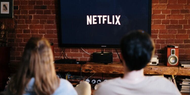 man and woman sitting on a couch in front of a television