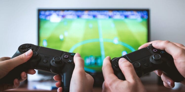 two people holding black gaming consoles