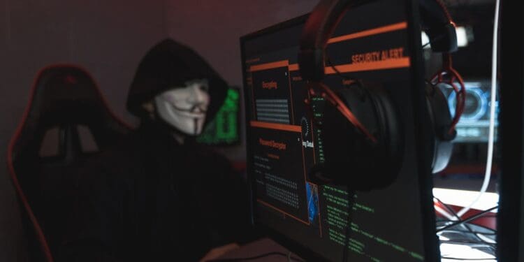 person in black hoodie hacking a computer system
