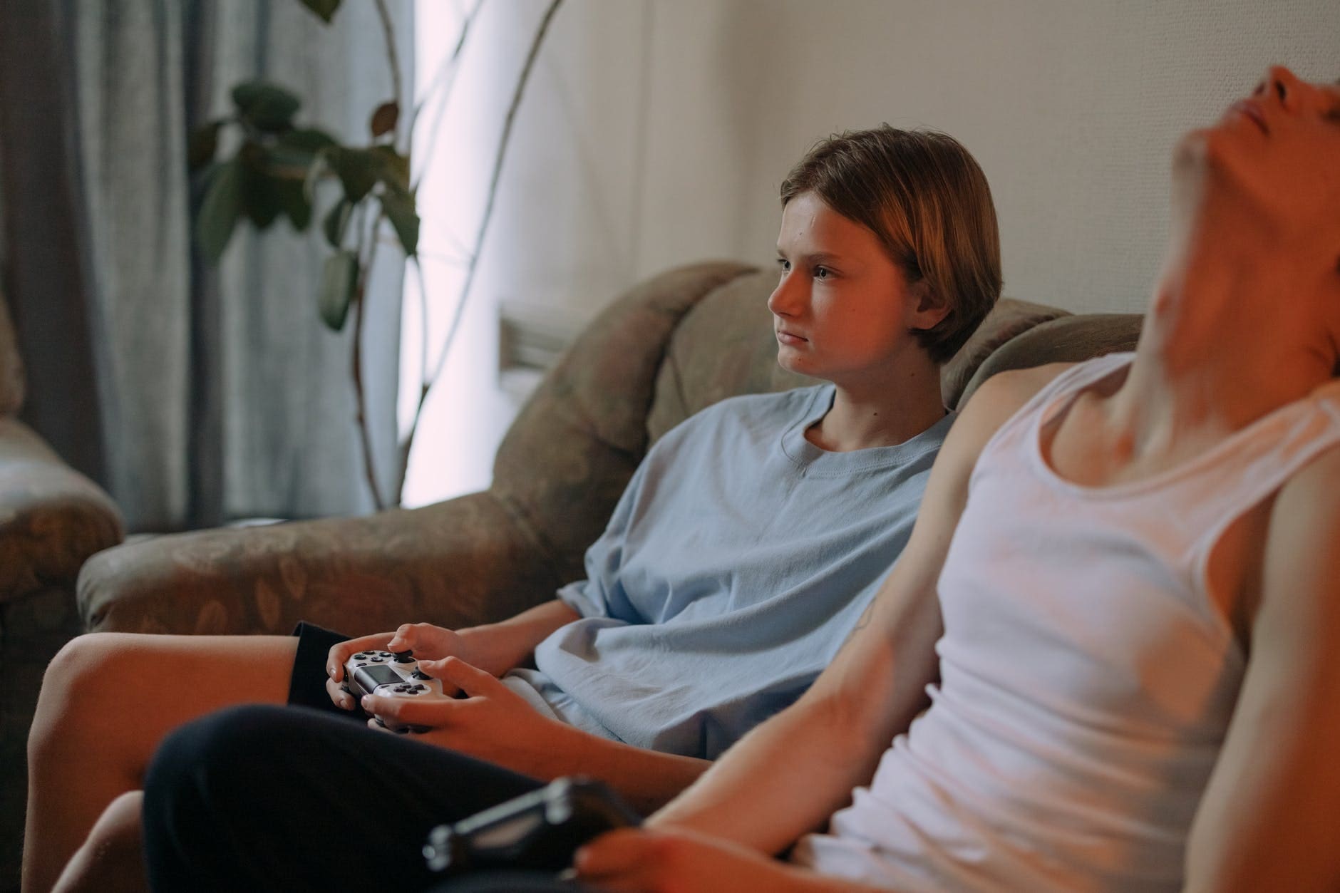 a young woman sitting beside a man on sofa holding a joystick
