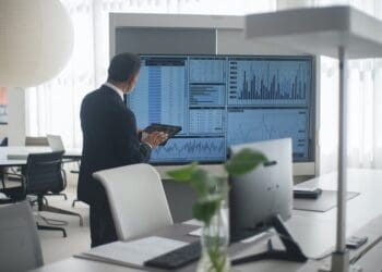 man looking at a screen with stock market data