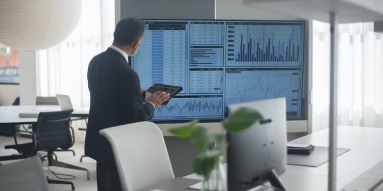 man looking at a screen with stock market data