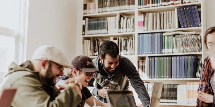 three men laughing while looking in the laptop inside room