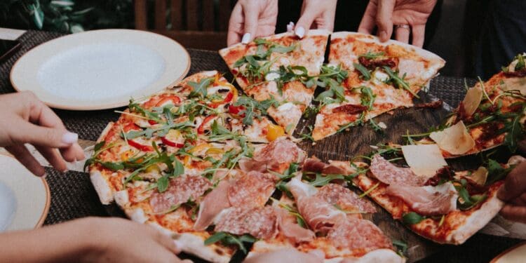 person holding pizza on white ceramic plate