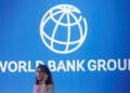 FILE PHOTO: A participant stands near a logo of World Bank at the International Monetary Fund - World Bank Annual Meeting 2018 in Nusa Dua, Bali, Indonesia, October 12, 2018. REUTERS/Johannes P. Christo/File Photo