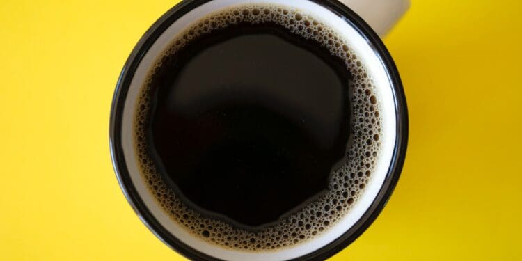 cup of black coffee on yellow surface