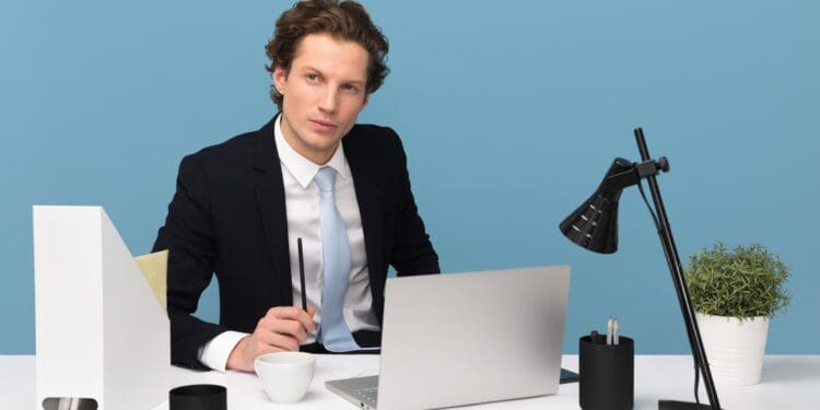 man sitting on chair beside laptop computer and teacup