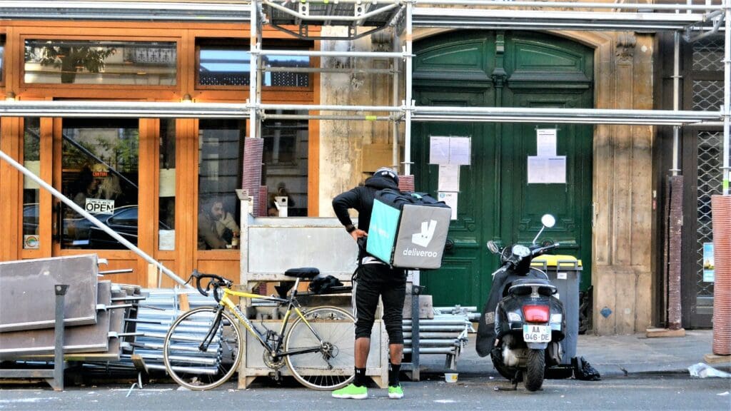 man in black jacket and black pants holding green and white book