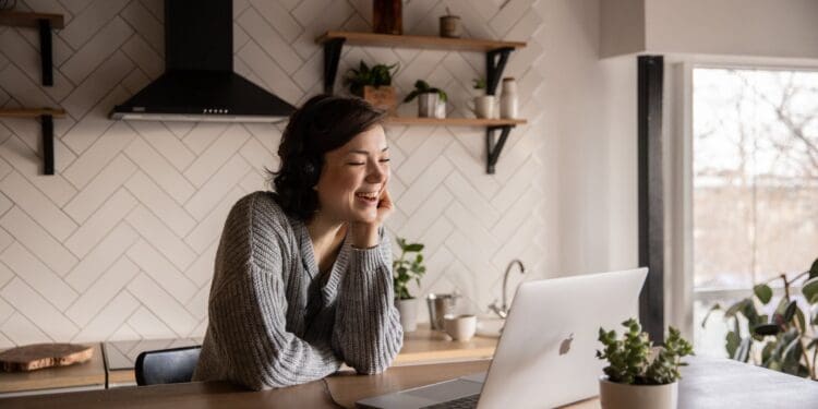 smiling woman talking via laptop in kitchen
