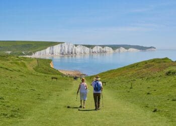 2 men standing on green grass field near body of water during daytime