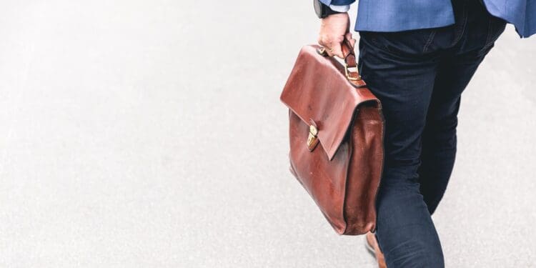 person walking holding brown leather bag