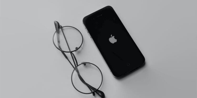 black iphone 4 beside black framed eyeglasses