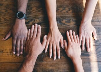 five human hands on brown surface