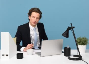 man sitting on chair beside laptop computer and teacup