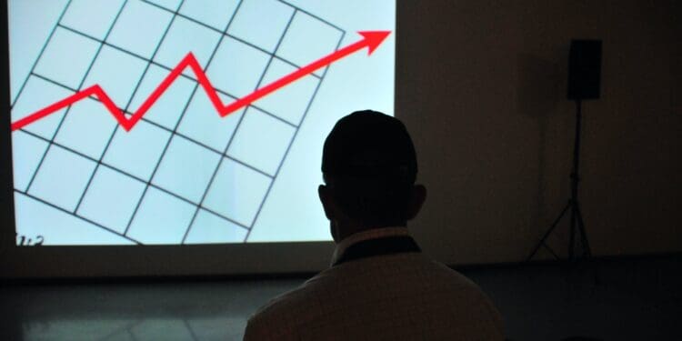 A man in front of a screen with a red arrow