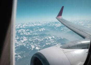 A plane's wing and motor seen from the window, above mountains.