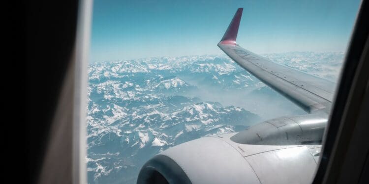 A plane's wing and motor seen from the window, above mountains.