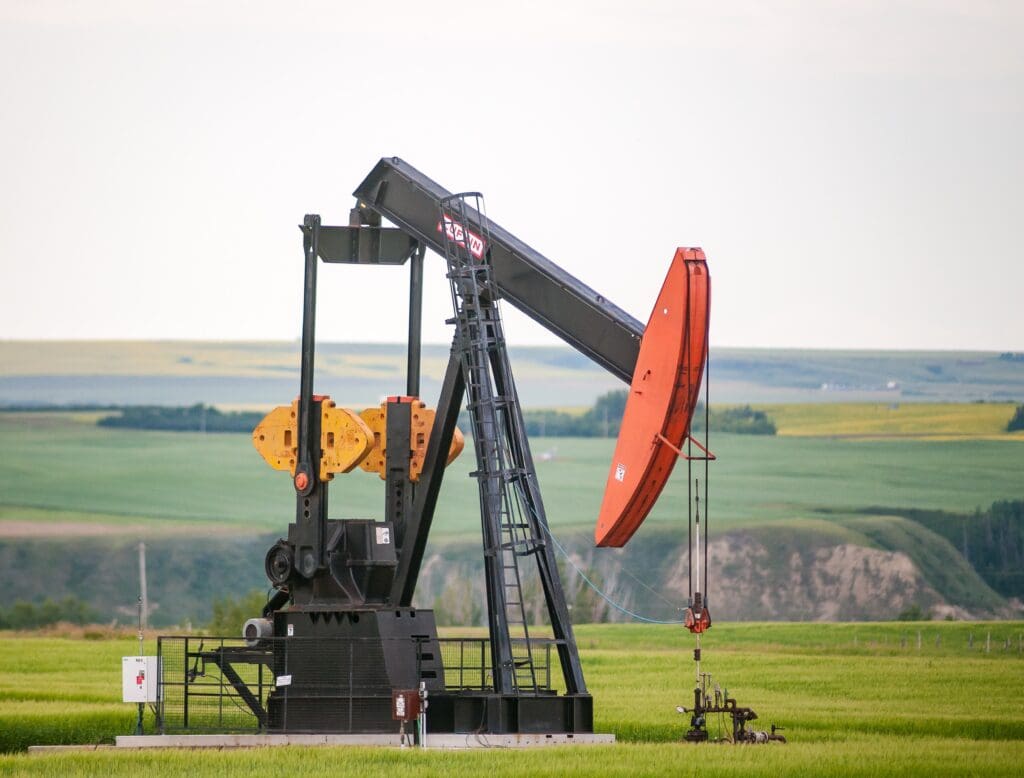 A pump jack sits in the middle of a Canola Field on the banks of the Red Deer River valley.