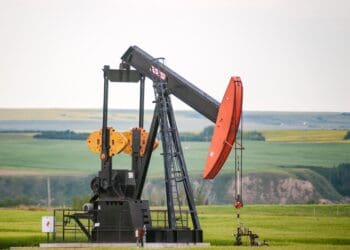 A pump jack sits in the middle of a Canola Field on the banks of the Red Deer River valley.