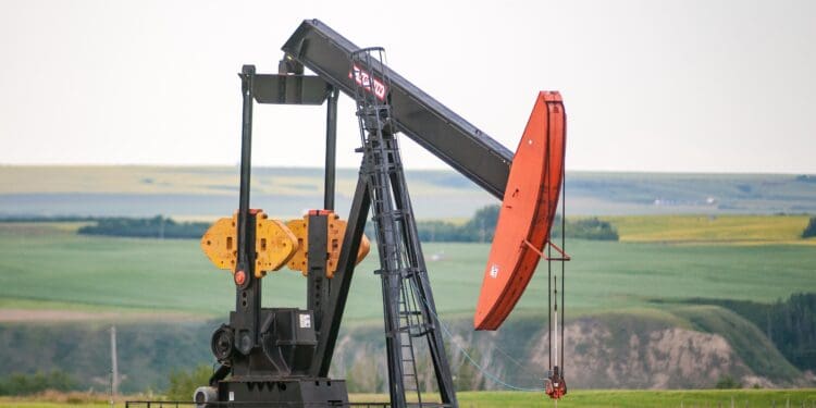 A pump jack sits in the middle of a Canola Field on the banks of the Red Deer River valley.