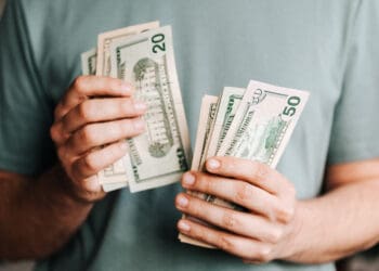 Crop man counting dollar banknotes
