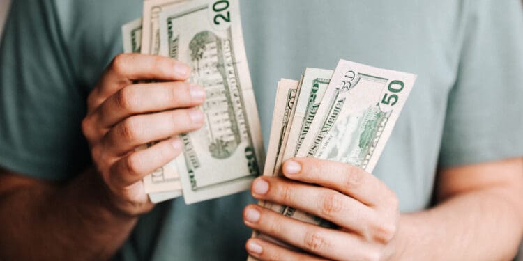 Crop man counting dollar banknotes