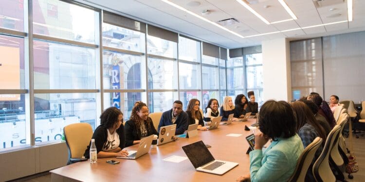group of people sitting beside rectangular wooden table with laptops