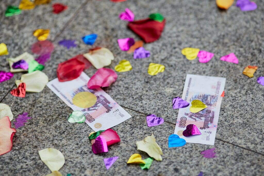 Two 500-ruble banknotes lie on a stone surface surrounded by rose petals and sequins. Backgrounds for websites about weddings and traditions in Russia and the world