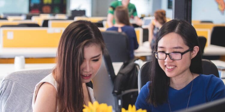 two women smiling in front of computer monitor