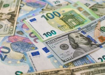 100 Euro (EUR), and 100 Dollar (USD) banknotes placed horizontally around other variety of banknotes.