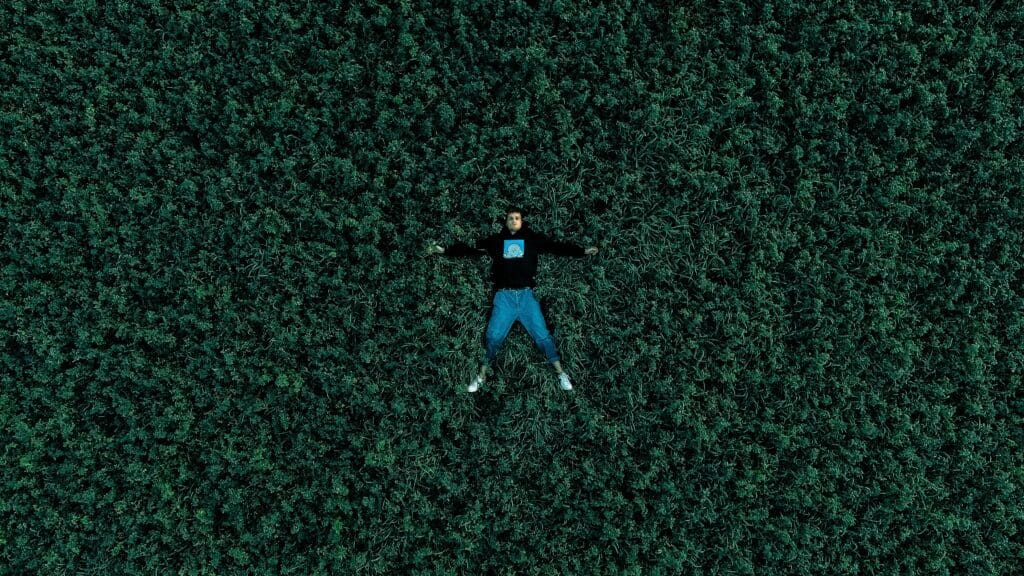 man in blue shirt and blue denim jeans lying on green grass field during daytime