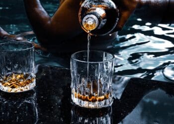 person pouring water on clear drinking glass