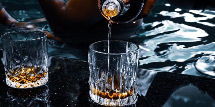 person pouring water on clear drinking glass
