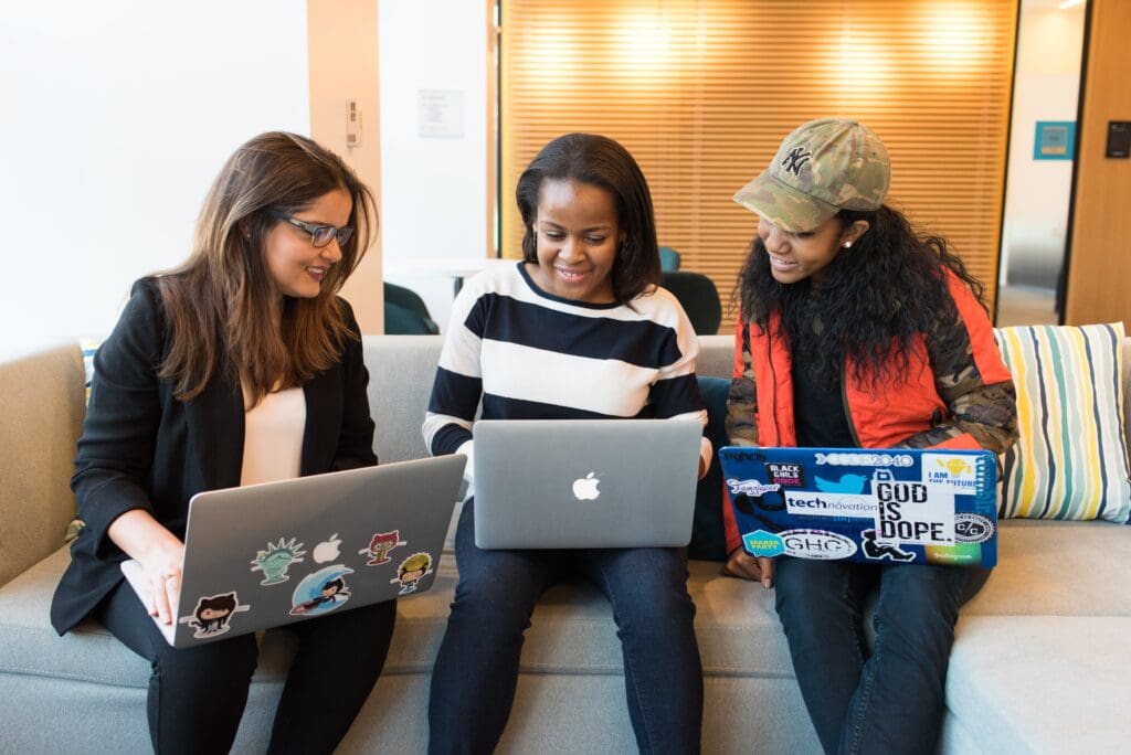 three women sitting on sofa with MacBook
