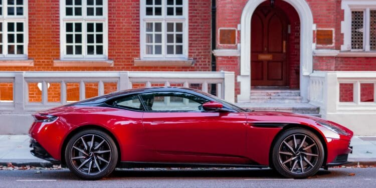 Red Aston Martin parked in front of a classical building in London.