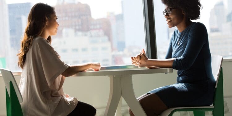 two women sitting beside table and talking