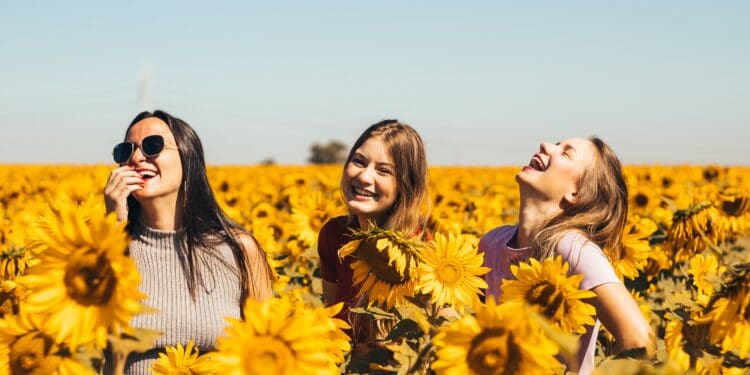 woman in white and black striped shirt standing on yellow sunflower field during daytime