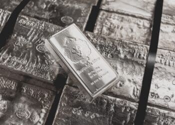 A Scottsdale Mint stacker bar sits on top of a pallet of raw silver.