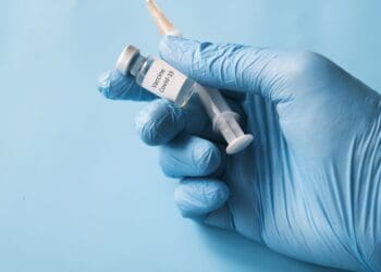 doctor hand in gloves holding coronavirus vaccine, close u.