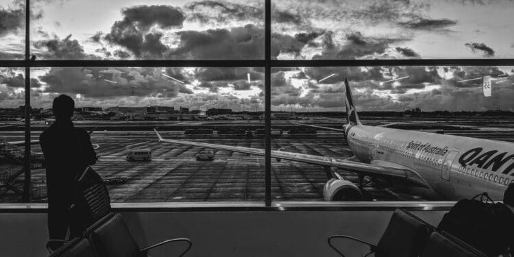 grayscale photography of man standing in front of plane