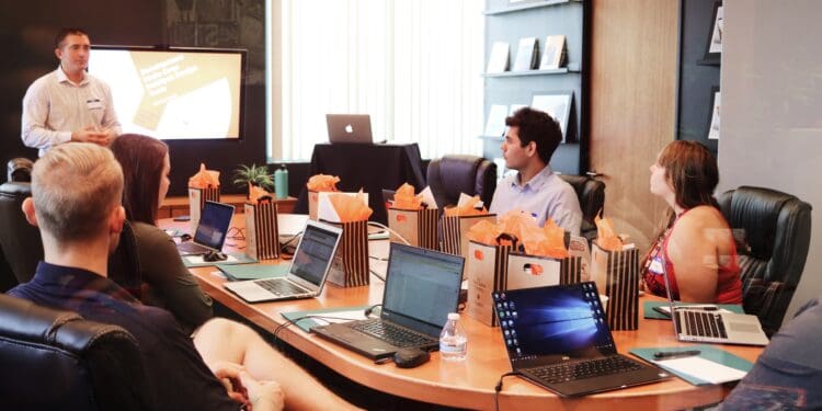 man standing in front of people sitting beside table with laptop computers