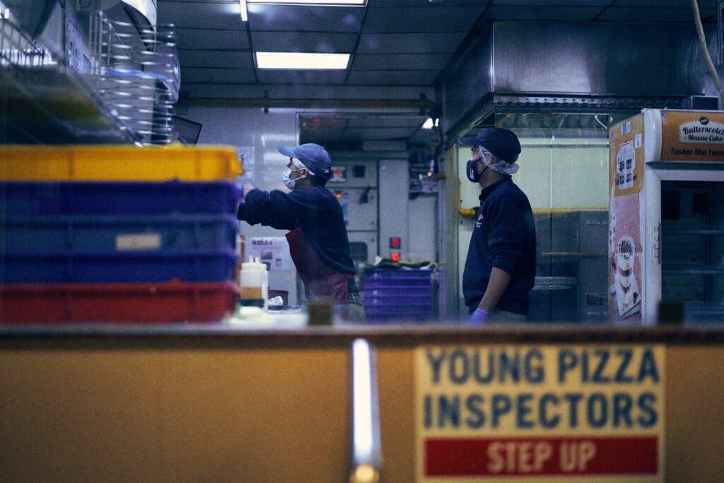 Two men wearing masks working at Domino's