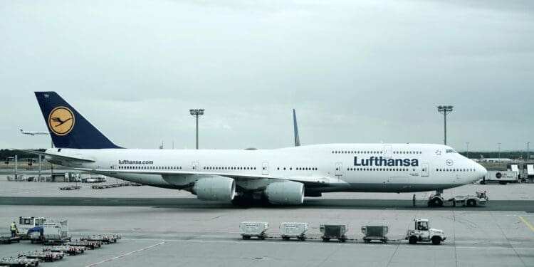 white and black Lufthansa airliner near vehicles