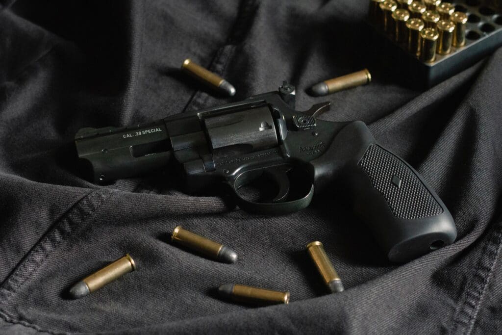 A black revolver on black cloth, with ammunition