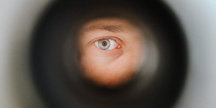 A green eye observing the outside world through a peephole in Berlin.