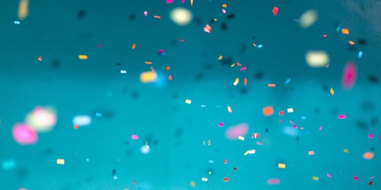 Colorful confetti falling down with a teal background